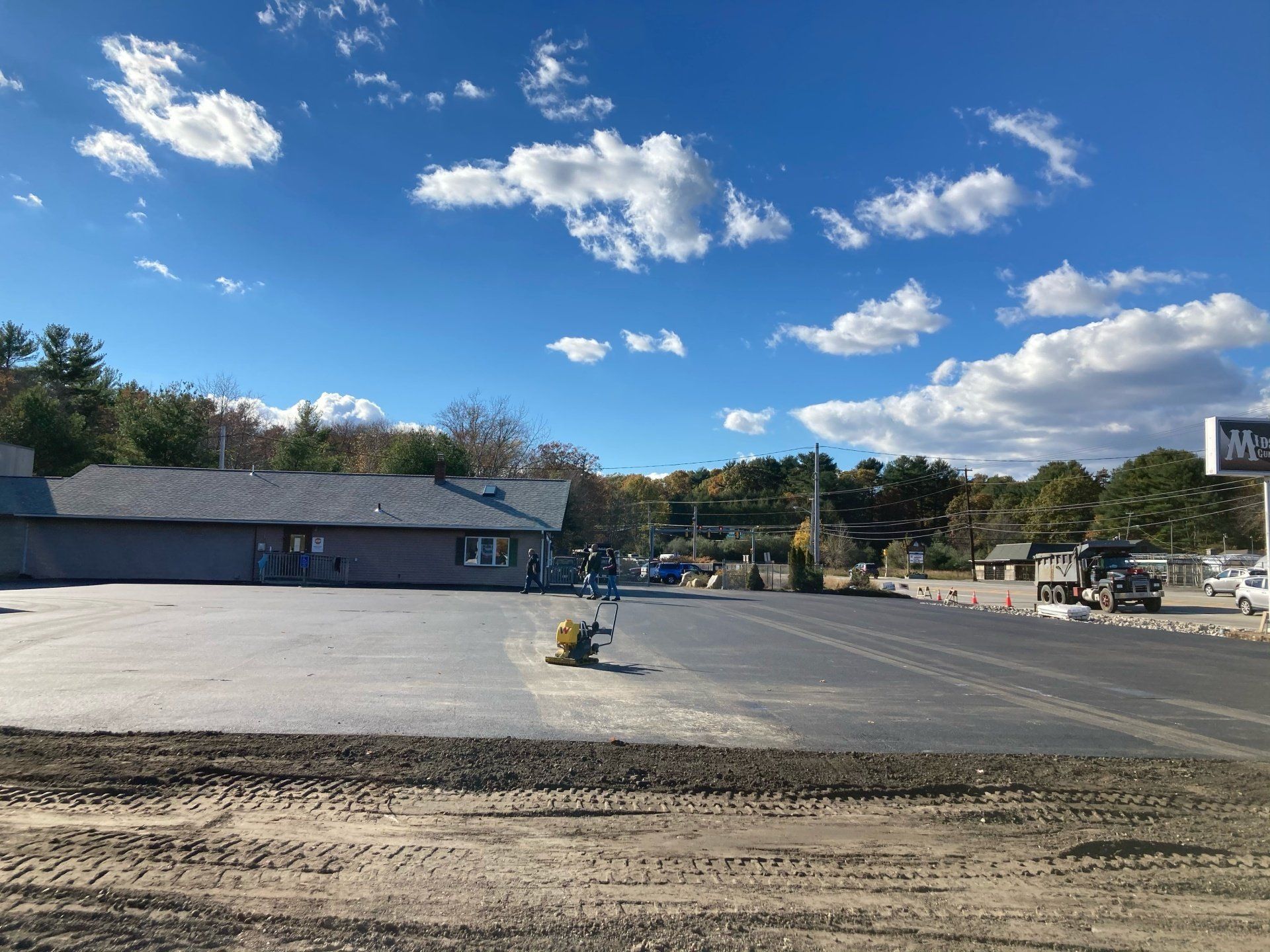 A large parking lot with a building in the background on a sunny day.