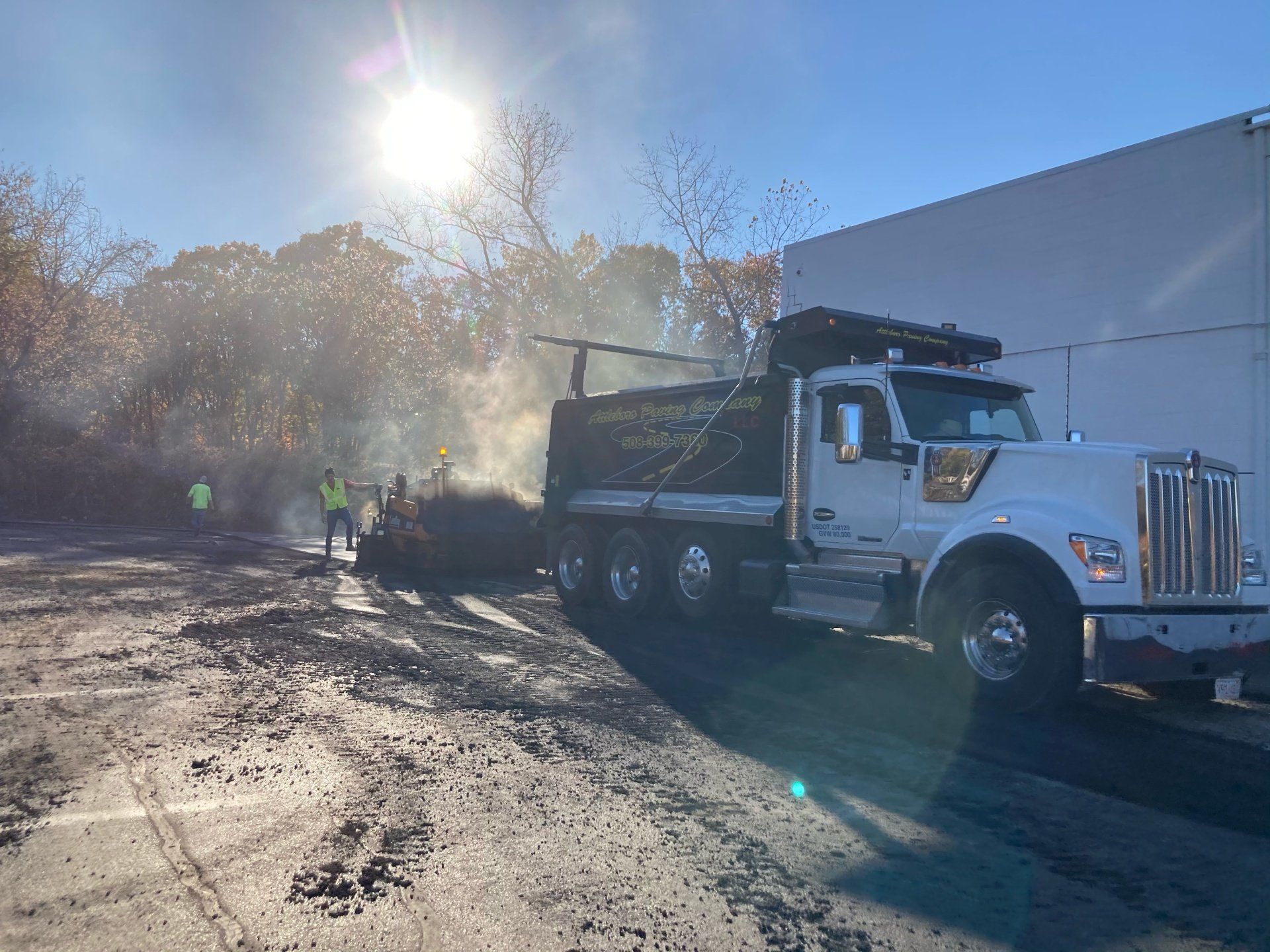A dump truck is parked in a parking lot next to a building.