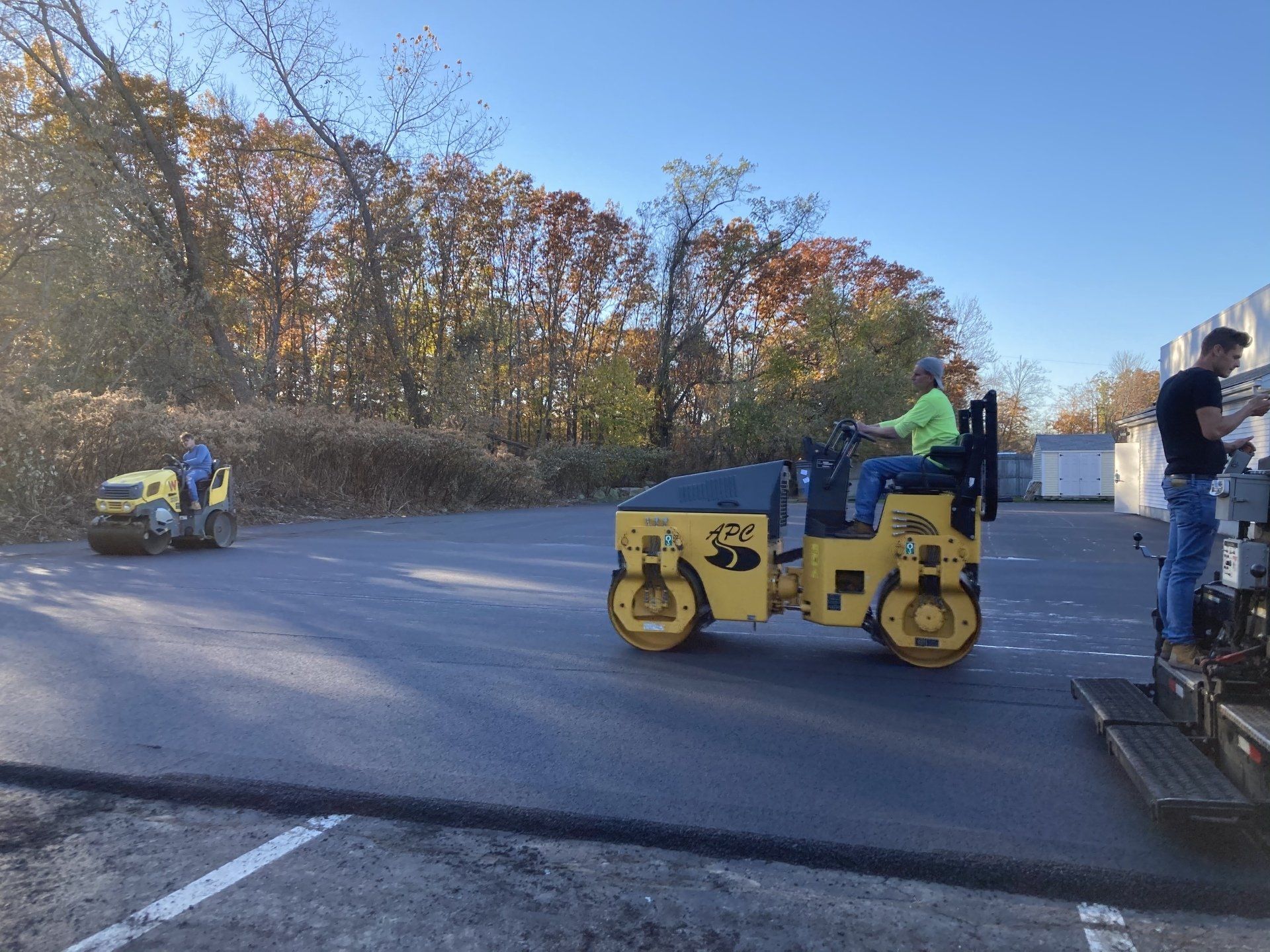 A man is driving a yellow roller in a parking lot.