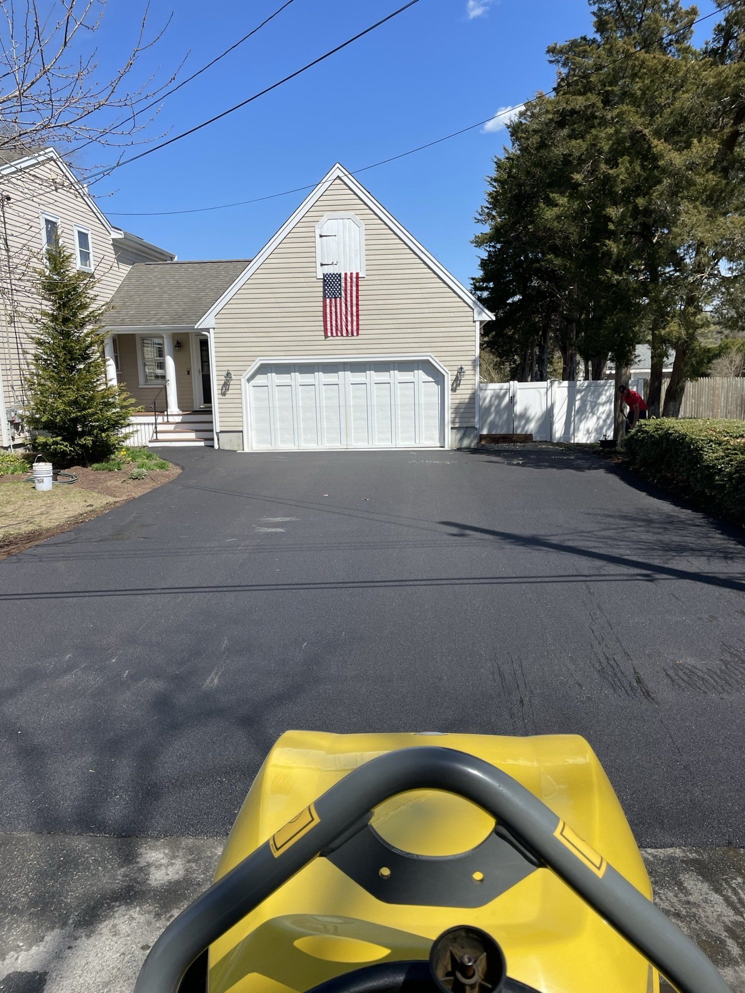 A yellow lawn mower is parked in front of a house