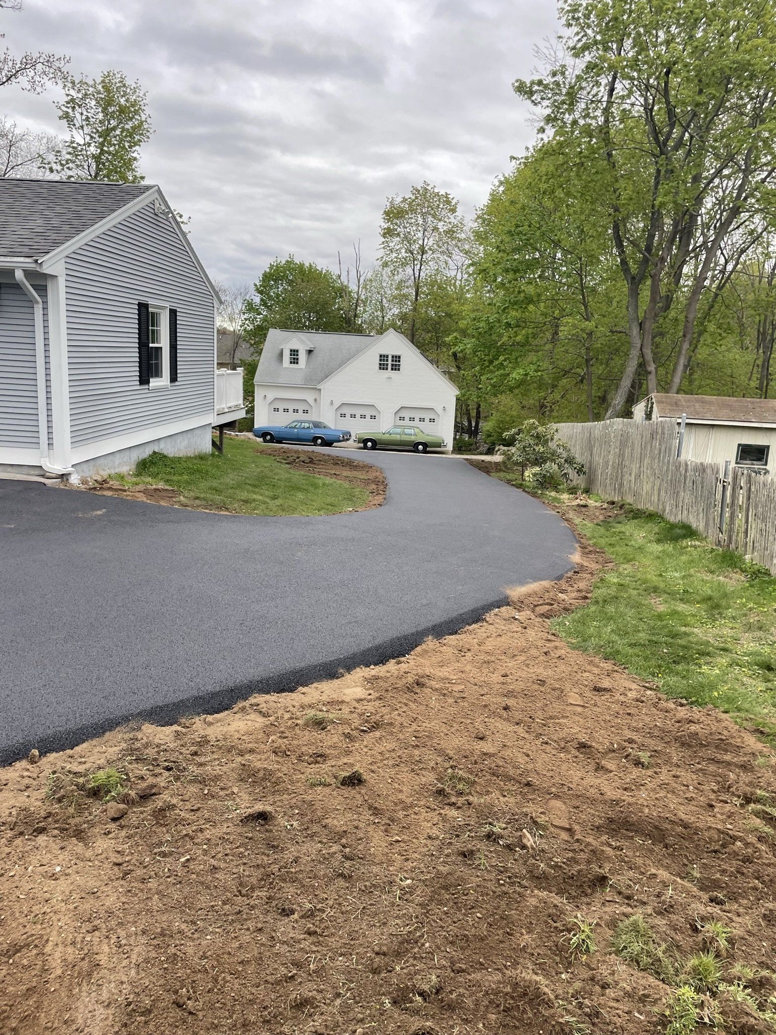 A driveway leading to a house with a car parked in front of it.