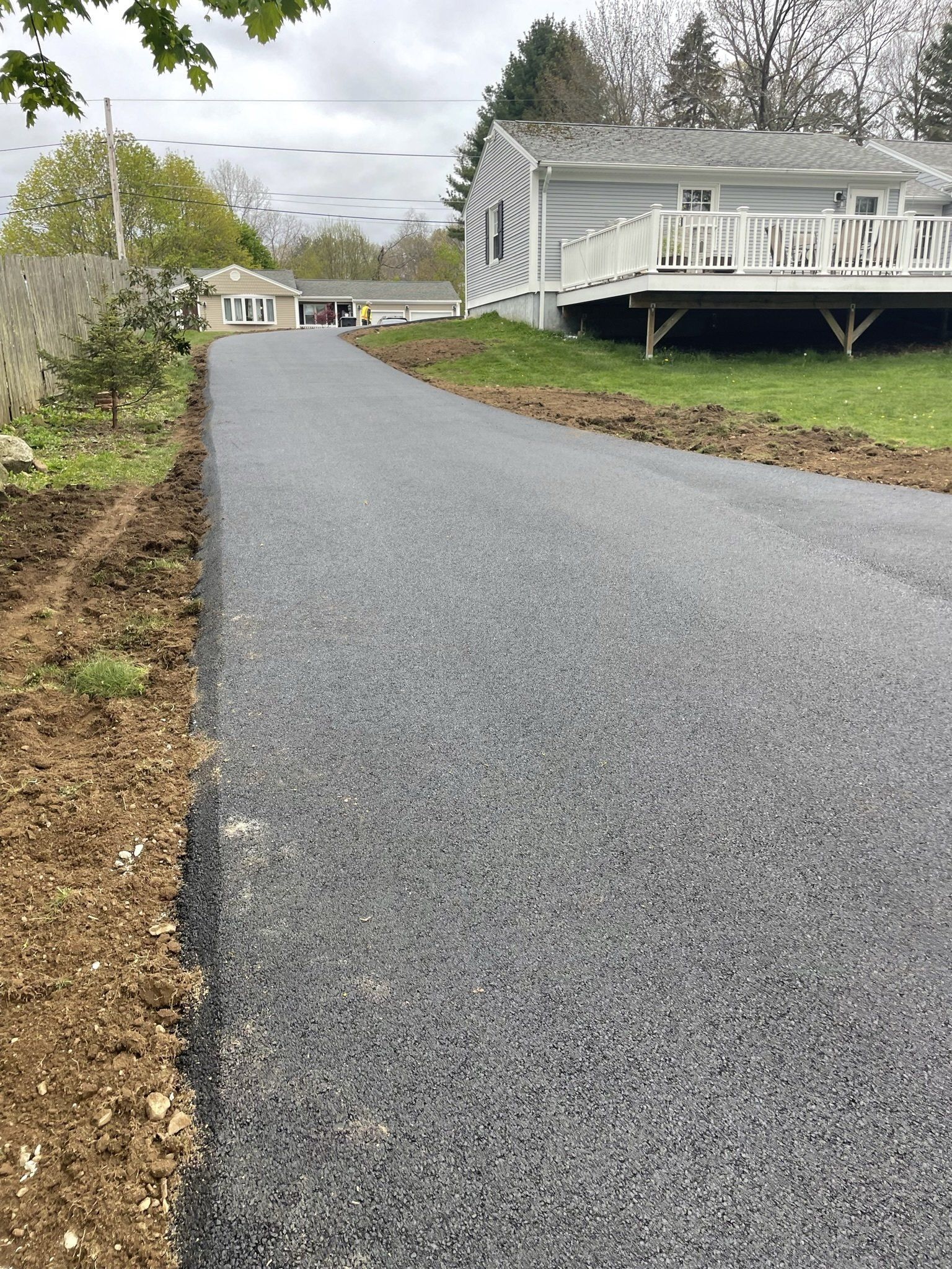 A newly paved driveway leading to a house with a deck.