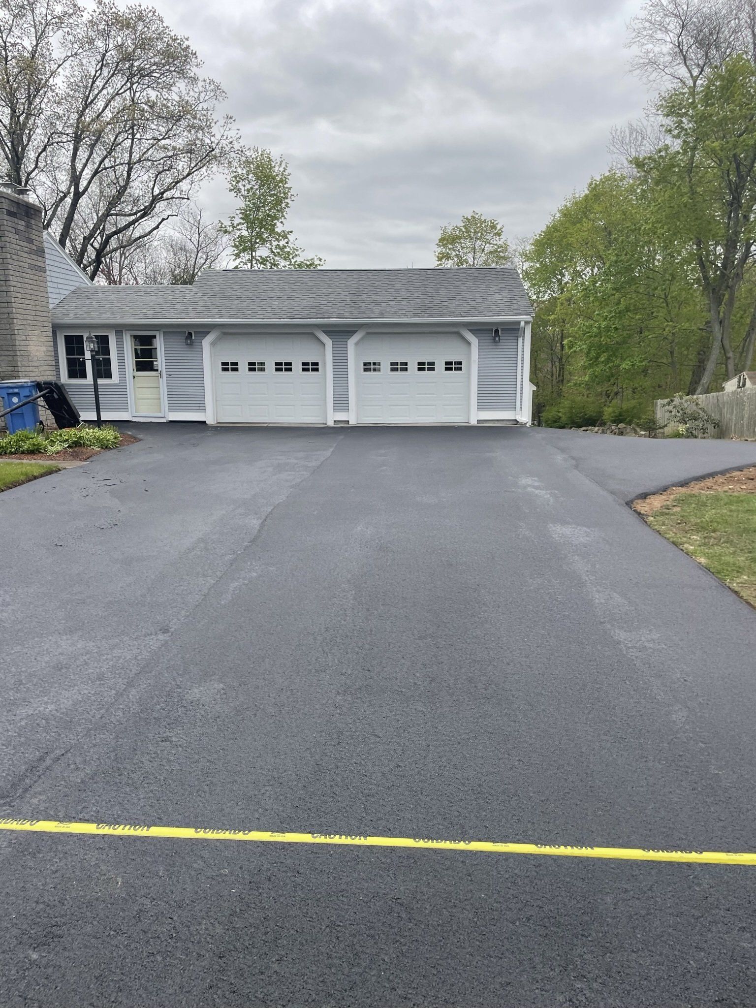 A driveway leading to a house with three garage doors.