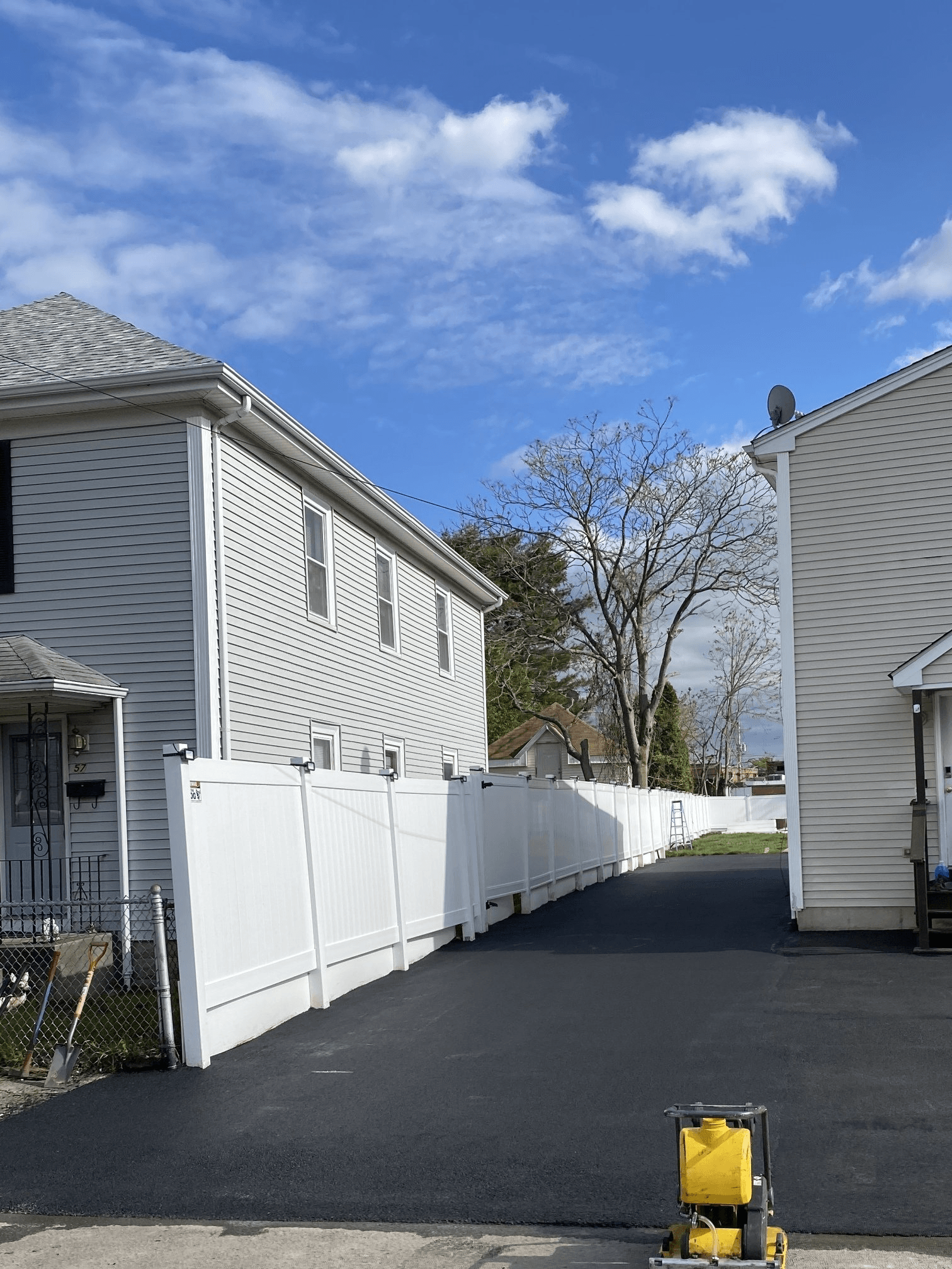A driveway leading to a house with a white fence.