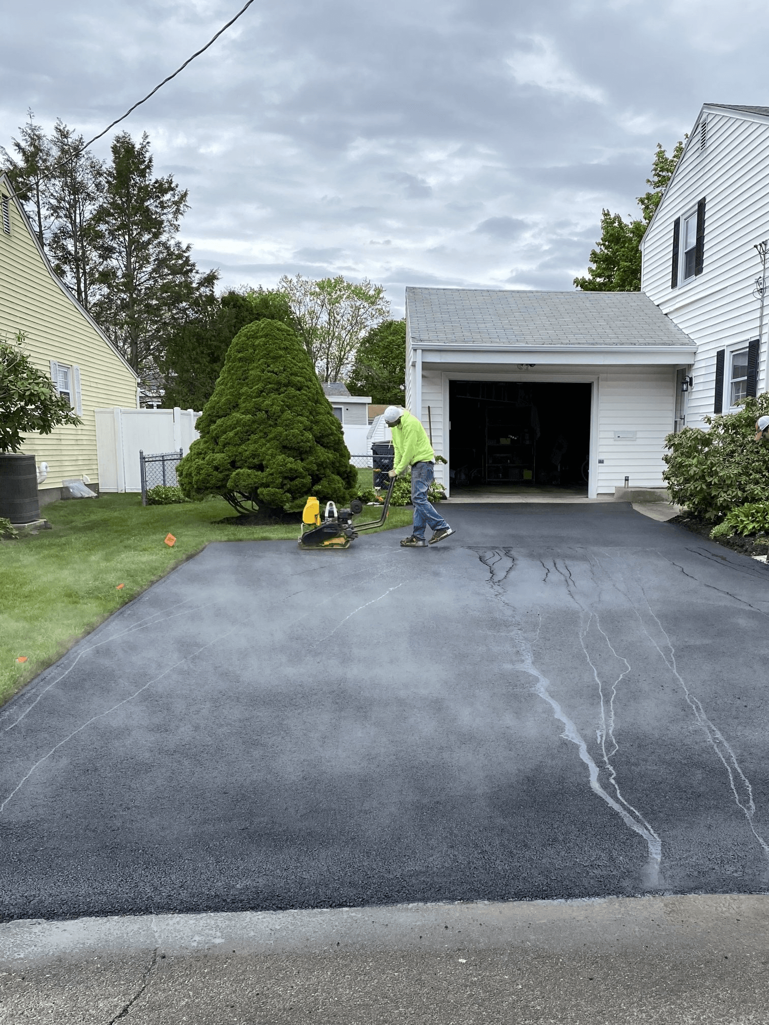 A man is painting a driveway in front of a house.