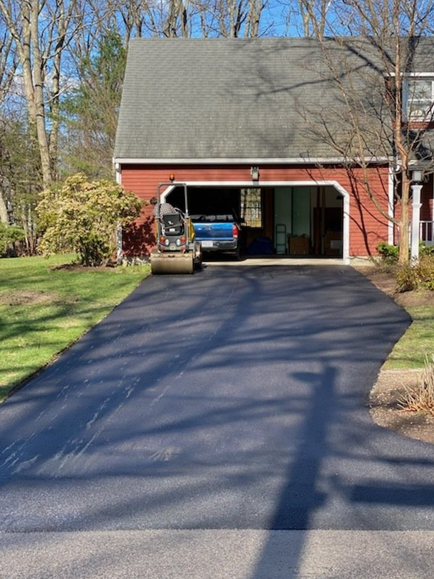 A truck is parked in a driveway in front of a red garage.
