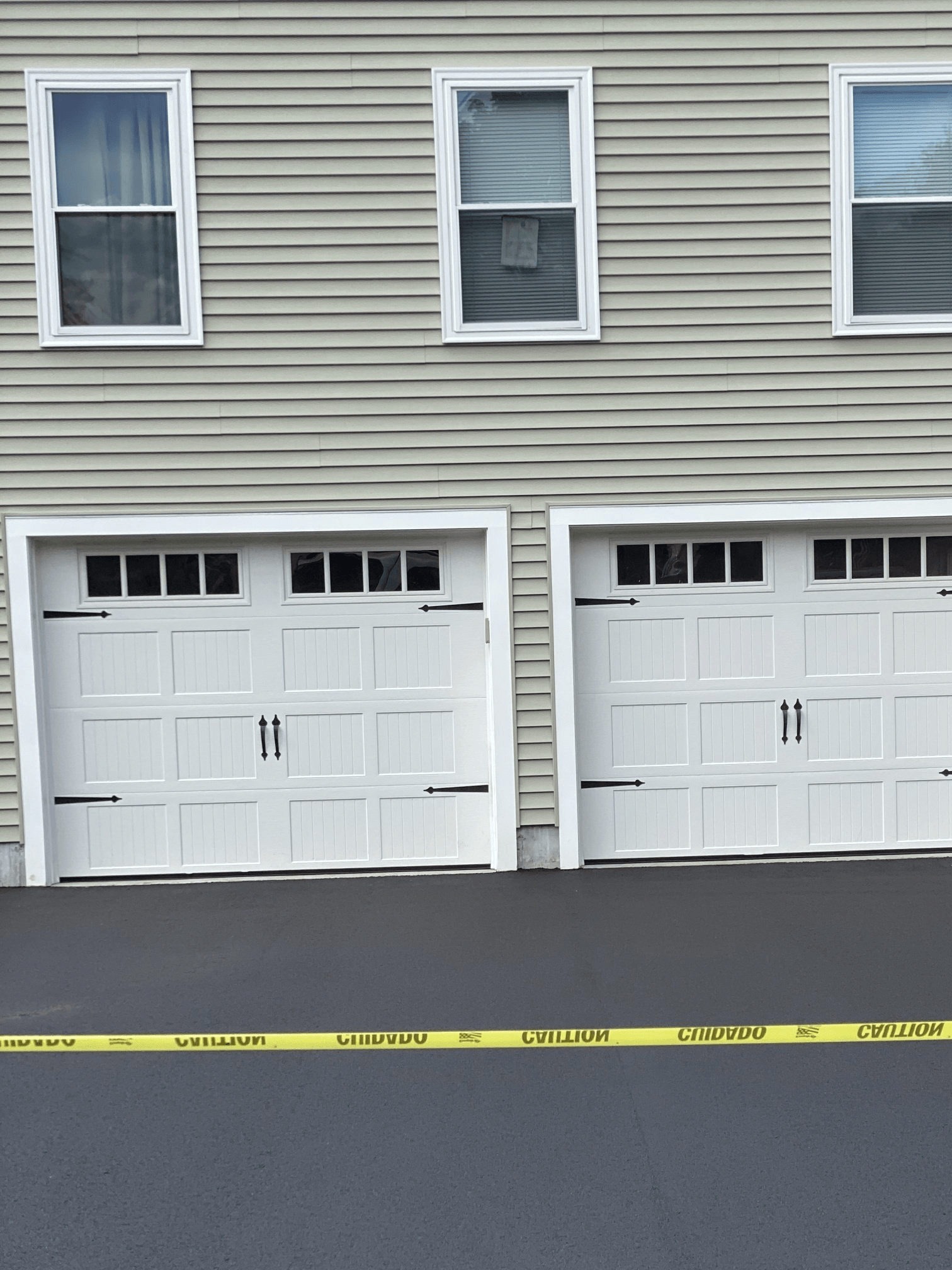 A house with two white garage doors and a yellow caution tape