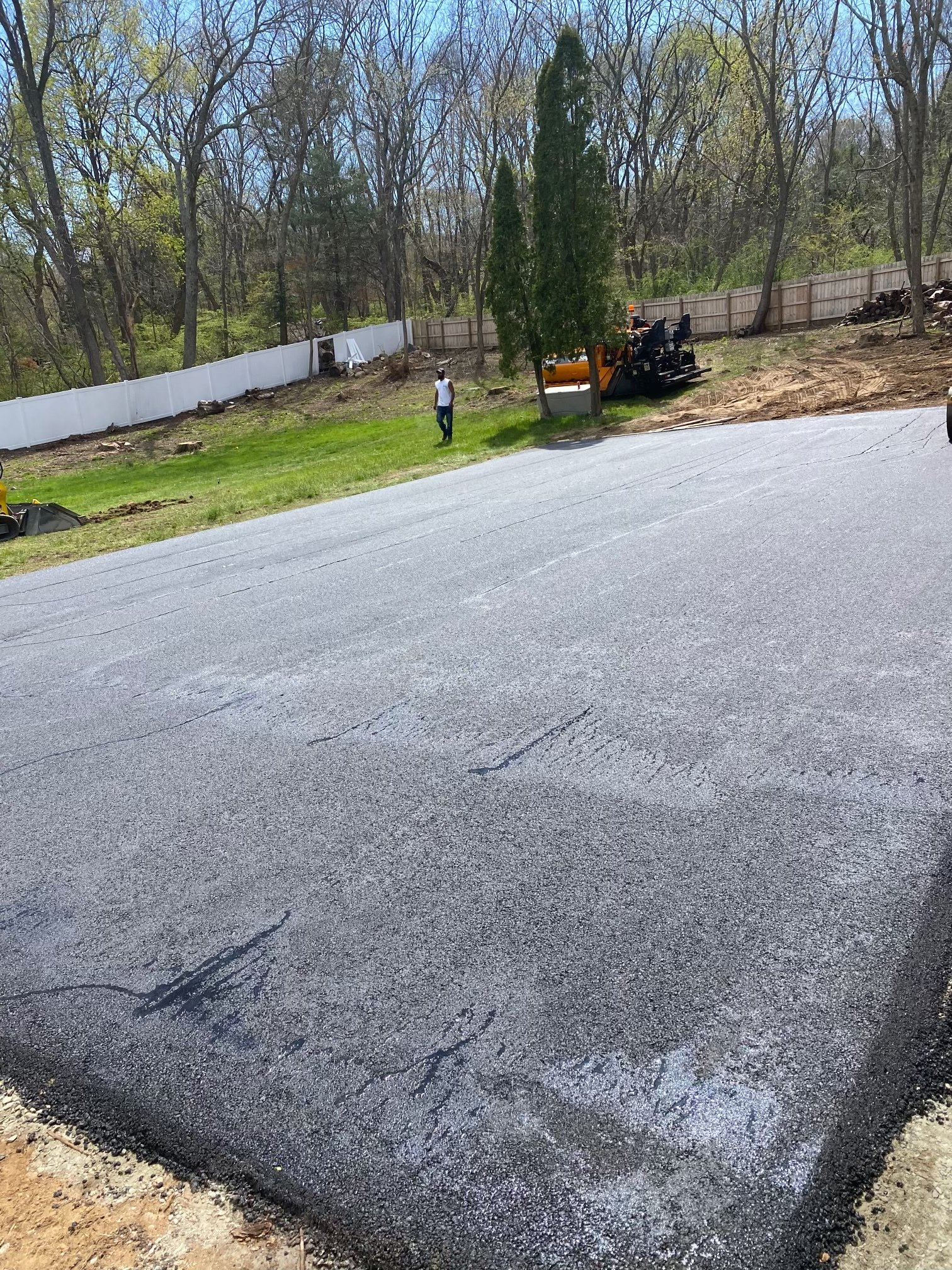 A man is standing in the middle of a paved driveway.