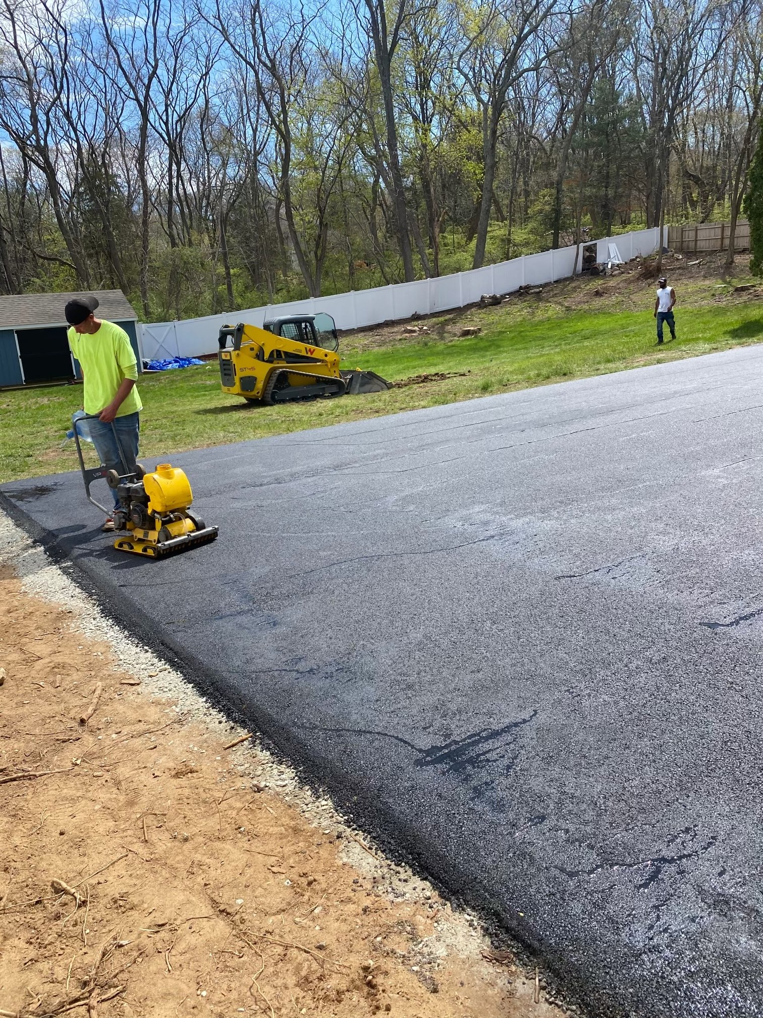 A man is paving a driveway with a compactor.