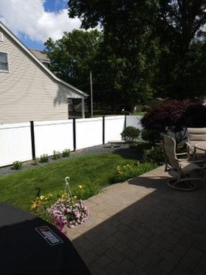 A backyard with a white fence and patio furniture.