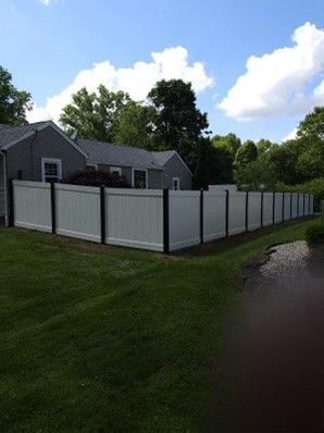 A white fence surrounds a lush green yard in front of a house