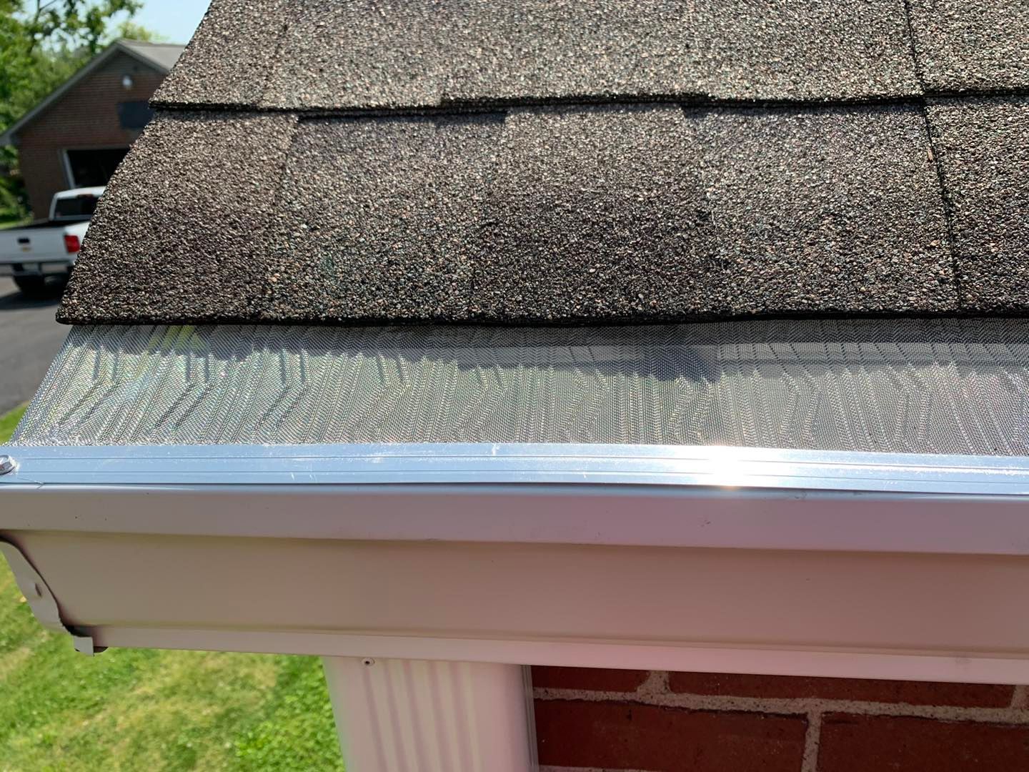 A gutter on the side of a house with a roof in the background