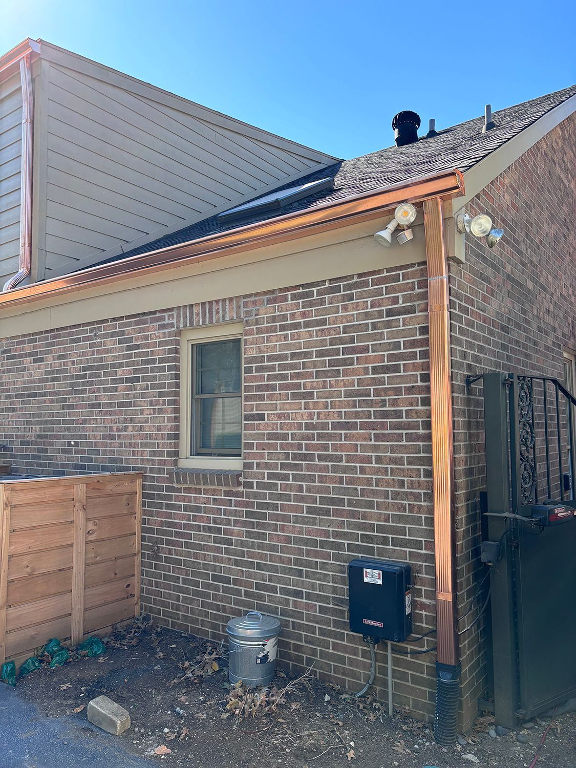 A brick house with a copper gutter on the side of it.