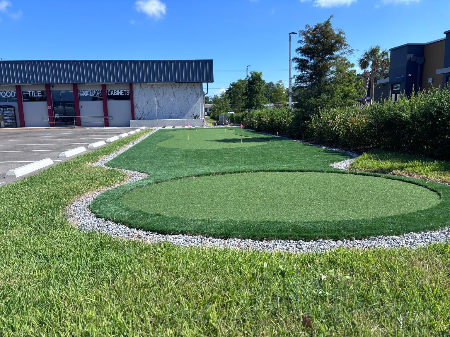 A putting green in front of a building on a sunny day