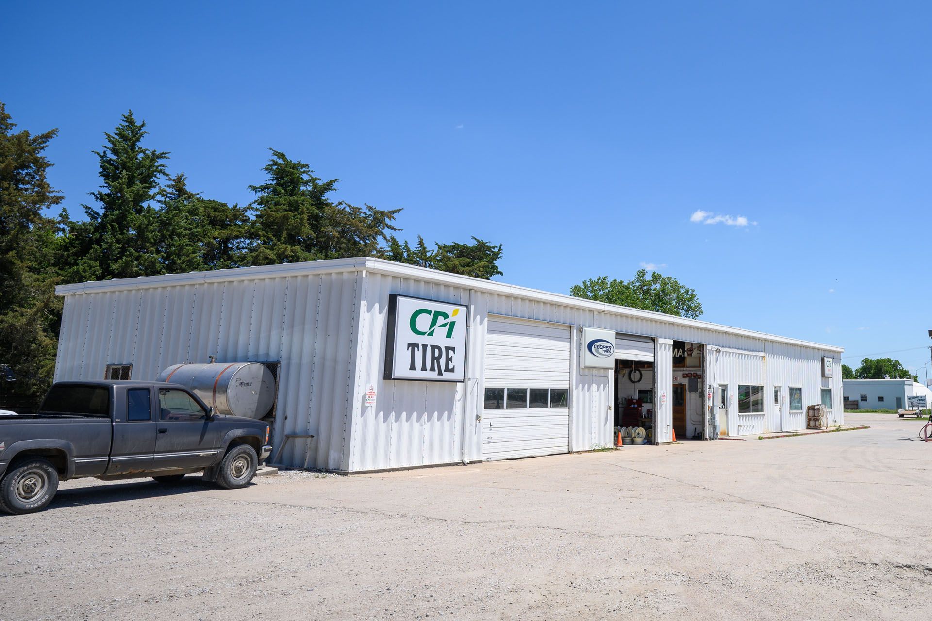 White tire shop building with a pickup truck parked outside under a clear blue sky