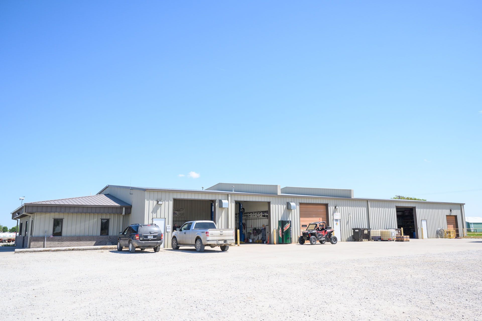 Desert roadside buildings with parked cars under a clear blue sky