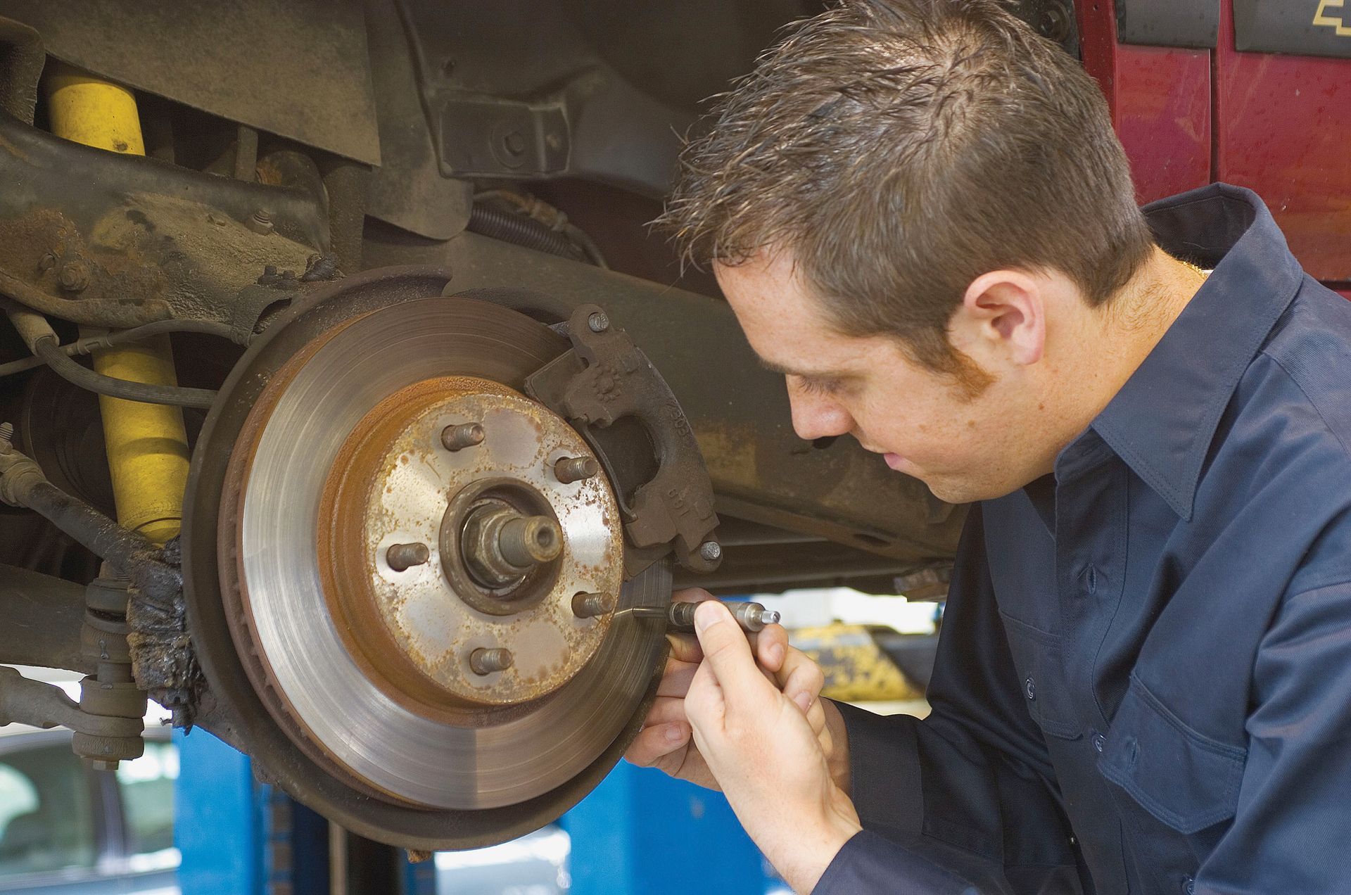 Mechanic inspecting a car brake rotor with a tool in a garage
