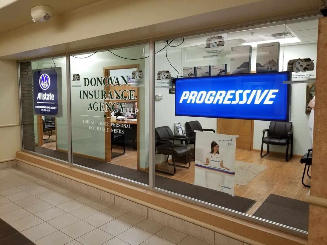 The street-level storefront of Donovan Insurance Agency with a large blue Progressive sign in the window.