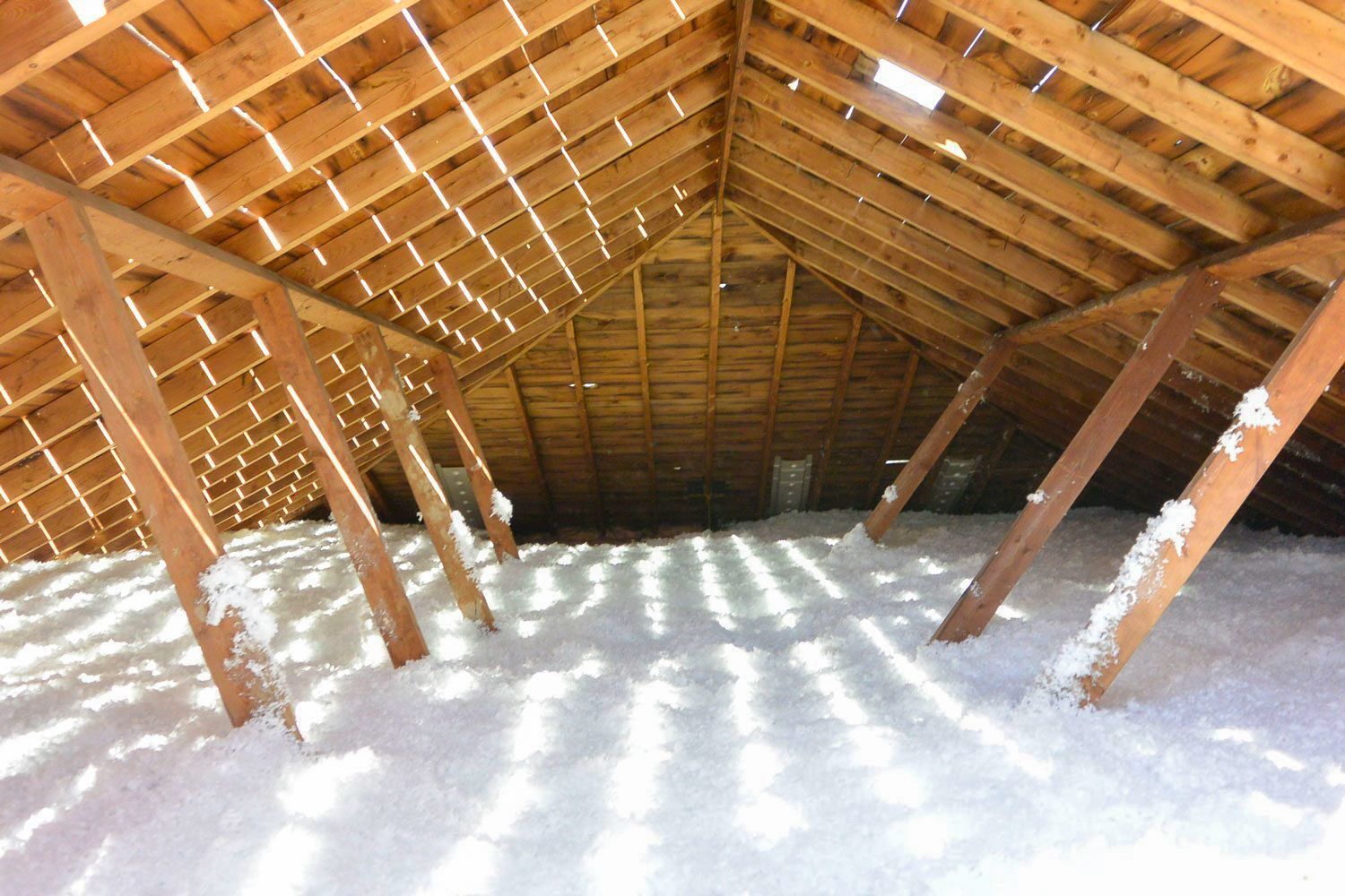 Attic with wooden rafters and cellulose insulation.
