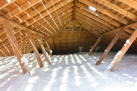 Attic with wooden rafters and cellulose insulation.