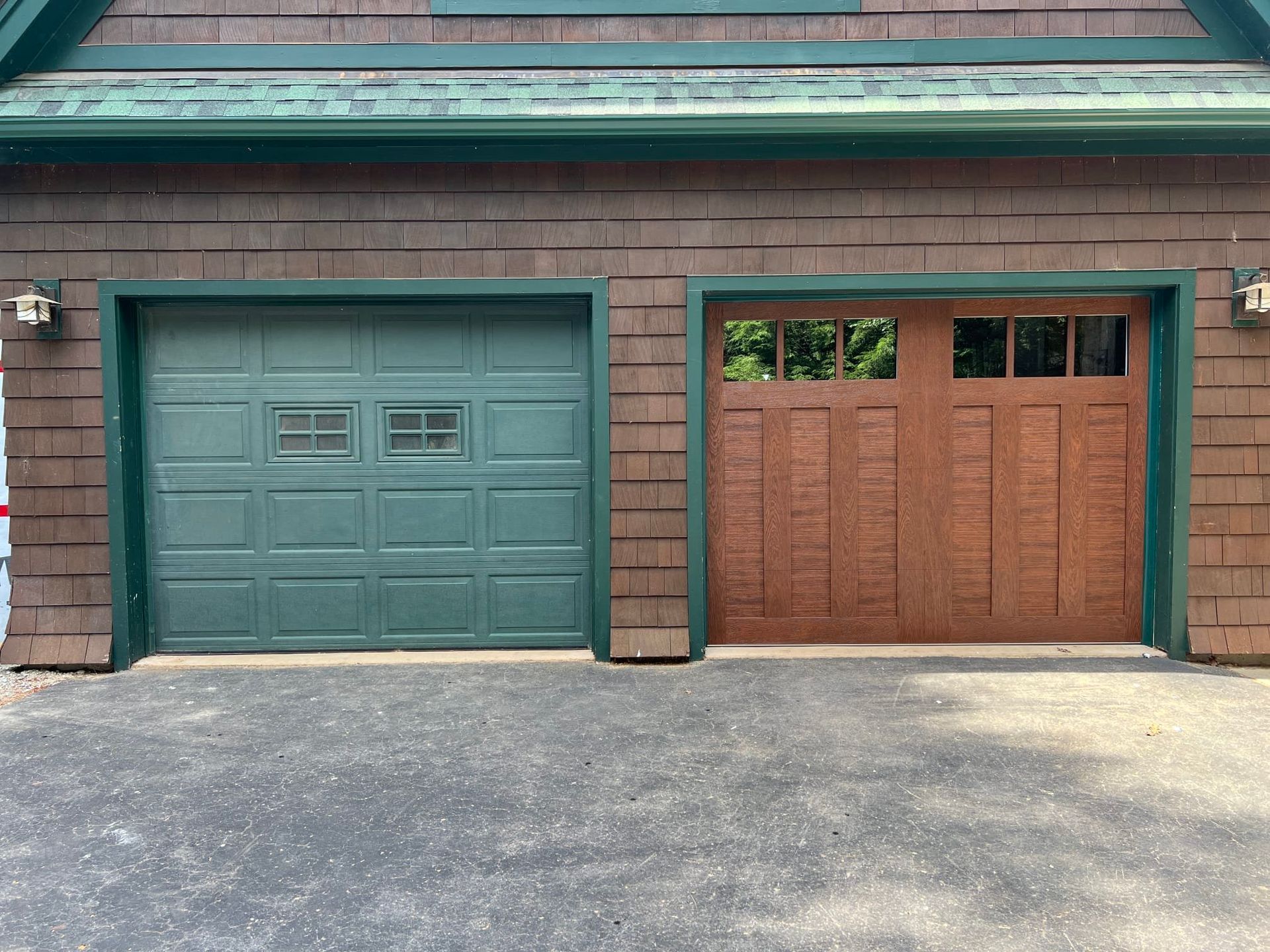 Side-by-side green and brown garage doors on a brick building.