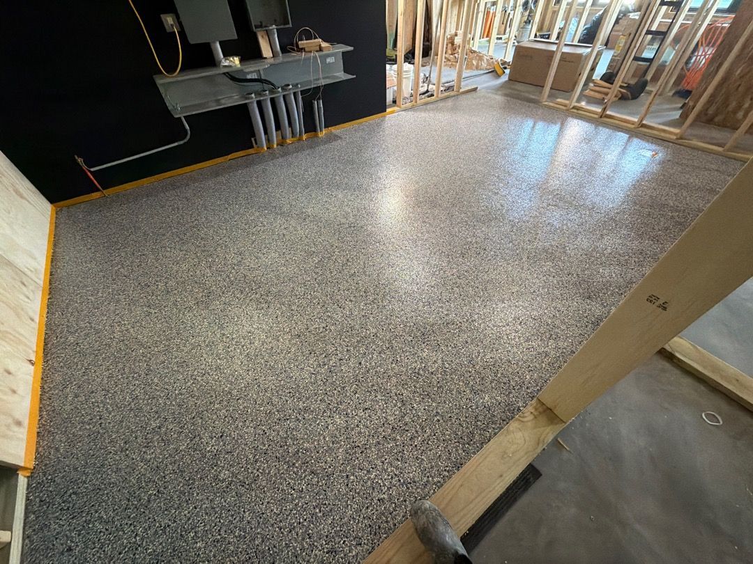 Indoor room with speckled epoxy floor, black walls, and exposed framing near a doorway.
