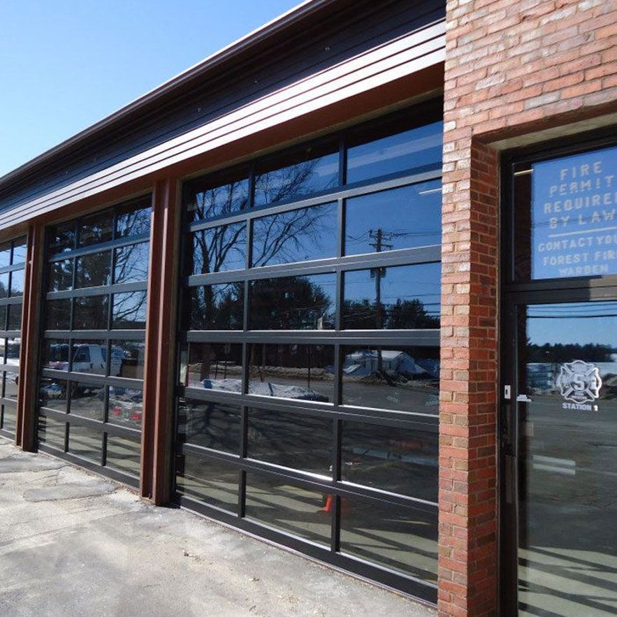 Fire station exterior with glass garage doors and a red brick facade.