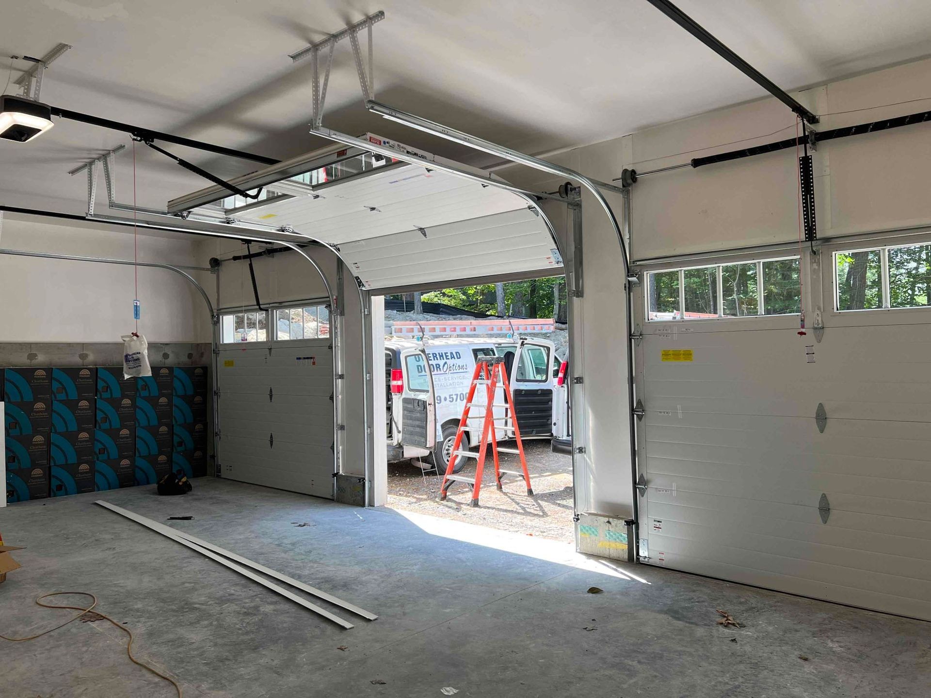 Garage with open doors; a work van and ladder visible inside.