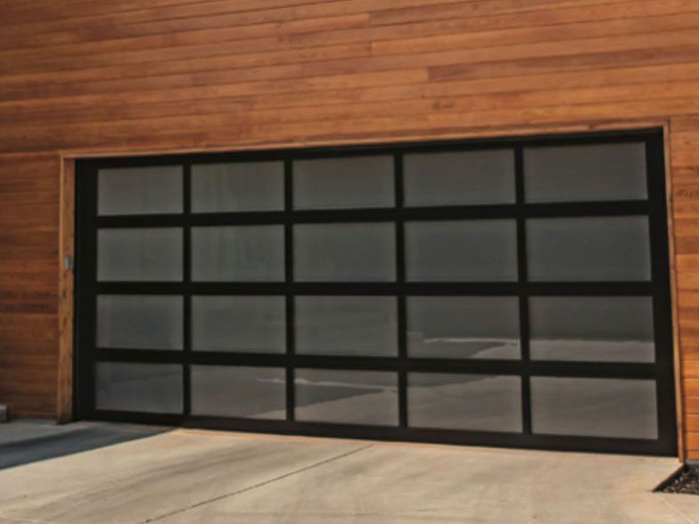 Black-framed, multi-paned glass garage door, against a brown wood-paneled wall, on a concrete driveway.