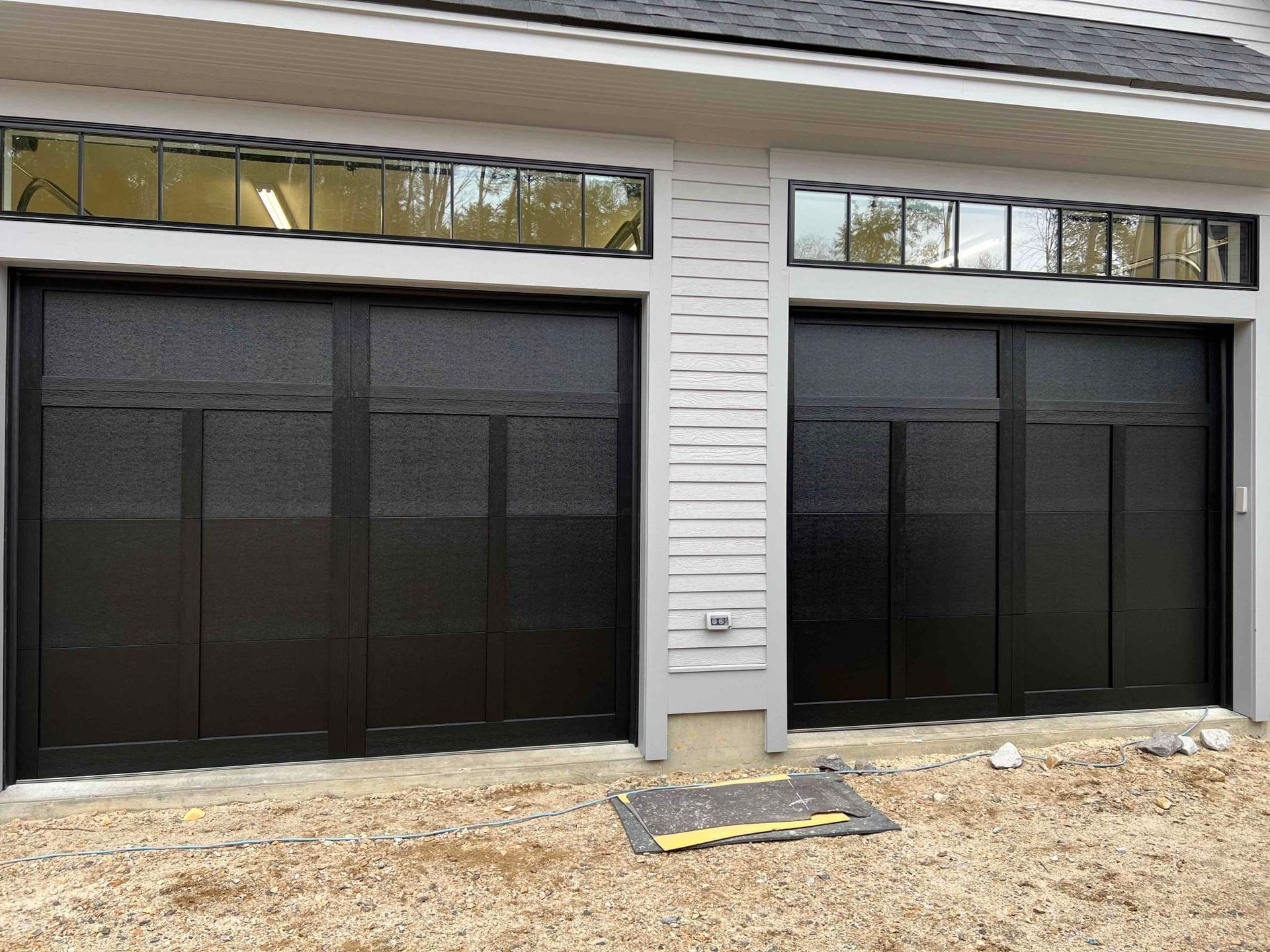 Two black garage doors with frosted glass panels and small windows above.