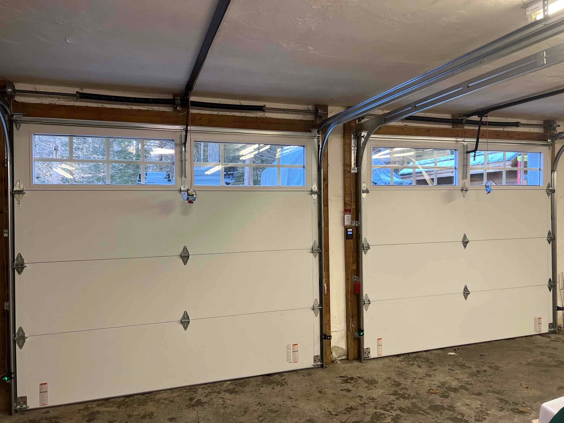 Two white garage doors with small window panes, interior view.