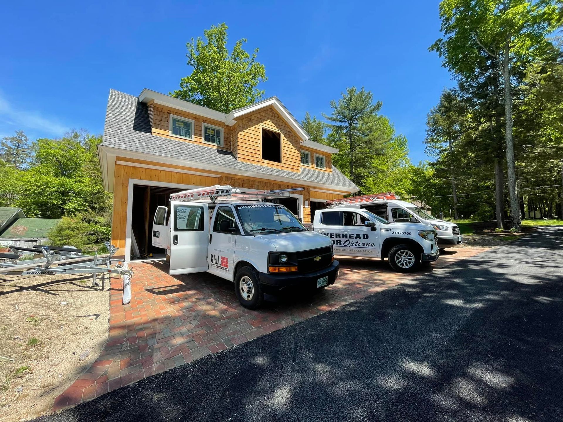 Two service vans parked in front of a partially built house, under a bright blue sky.