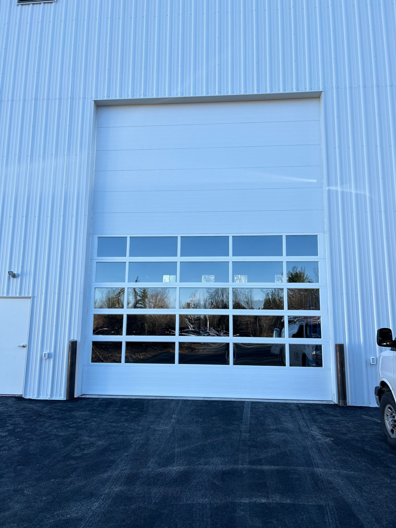 White building with large, glass-paneled garage door; paved area in front.