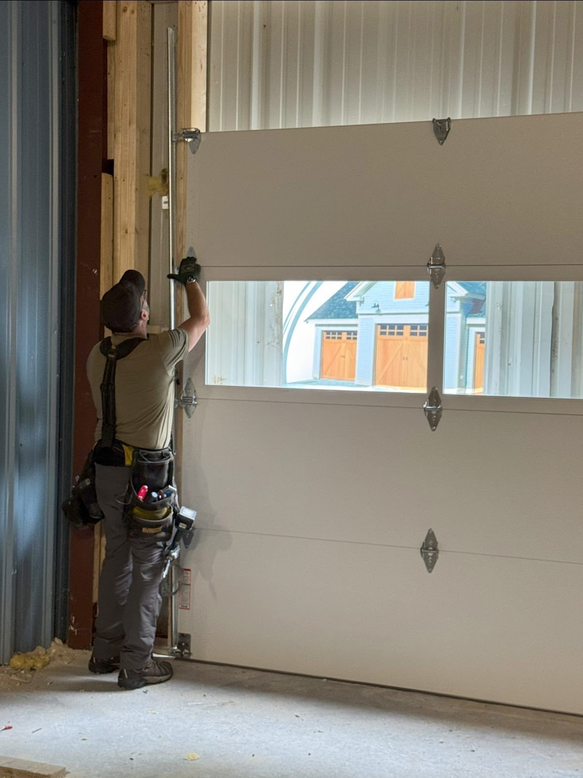 A construction worker installs a white garage door.