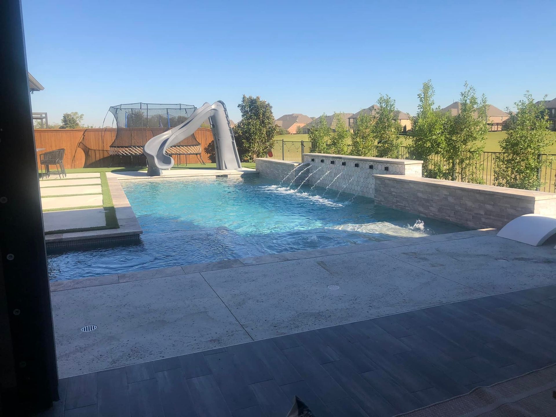A large swimming pool with a water slide in the backyard.