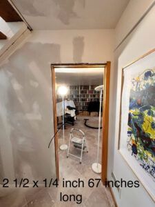 A doorway in a home under renovation, with text overlay specifying a measurement of 2 1/2 x 1/4 inches, 67 inches long.