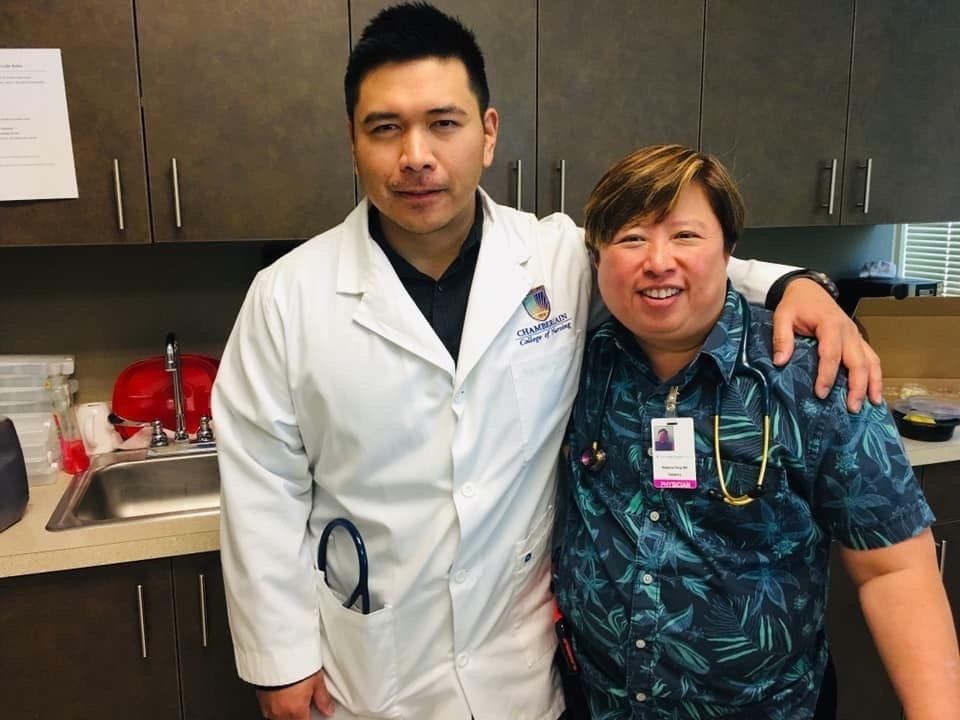 A doctor and a nurse are posing for a picture in a kitchen.