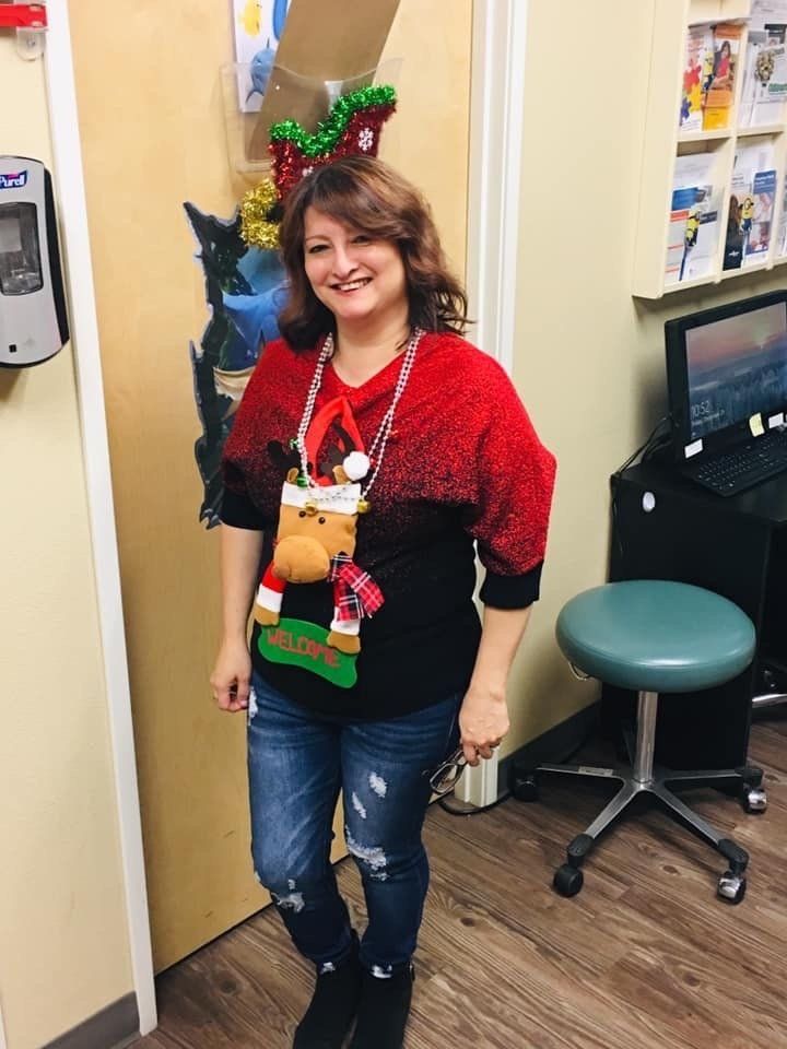 A woman wearing a christmas sweater and reindeer antlers is standing in a room.