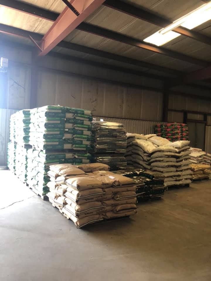Large stacks of bags containing various materials stored on pallets in a warehouse.