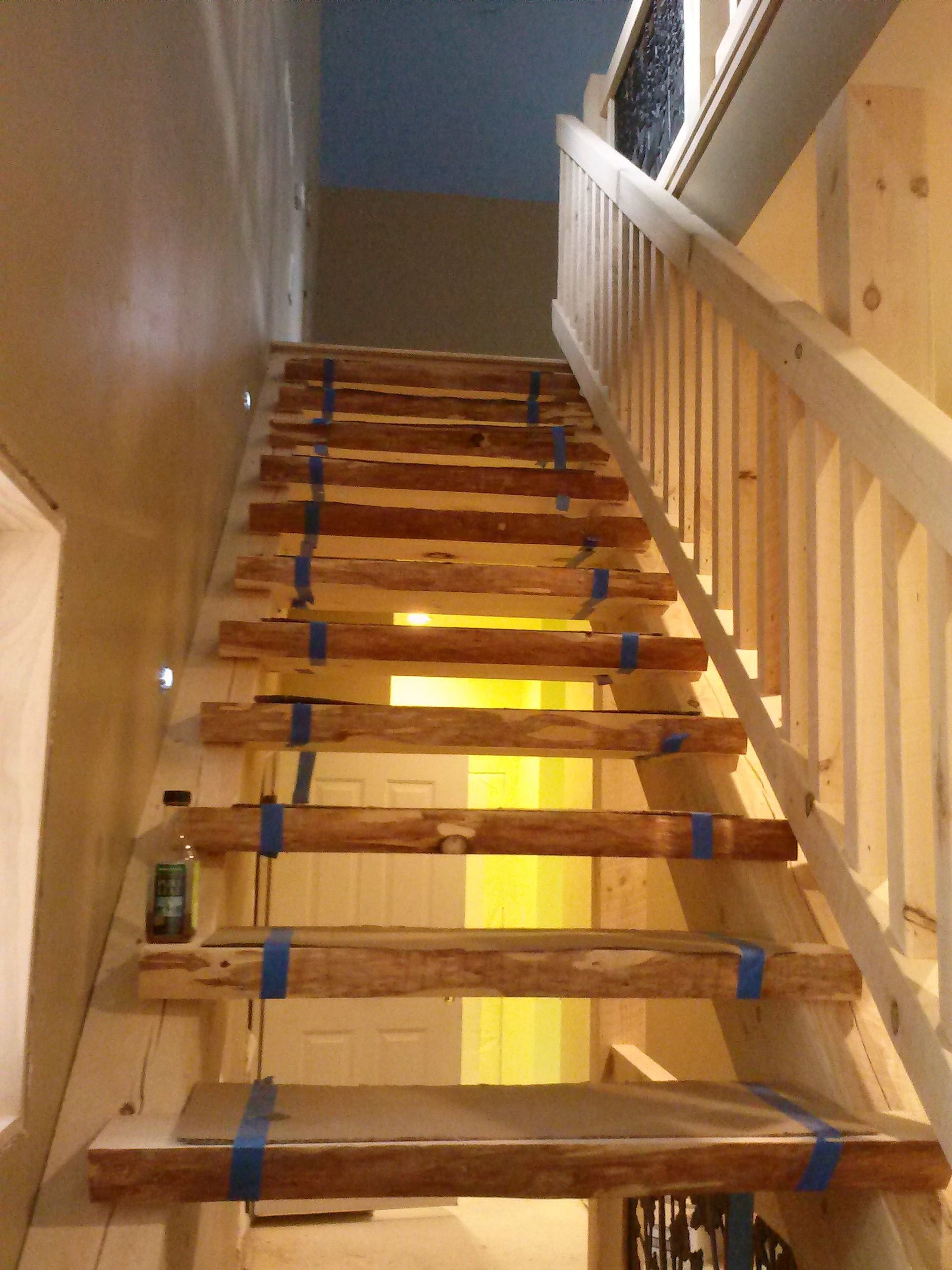 Unfinished wooden stairs with blue tape and bright light shining through gaps.