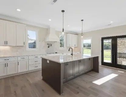 Modern kitchen with white cabinets, dark island, and French doors.