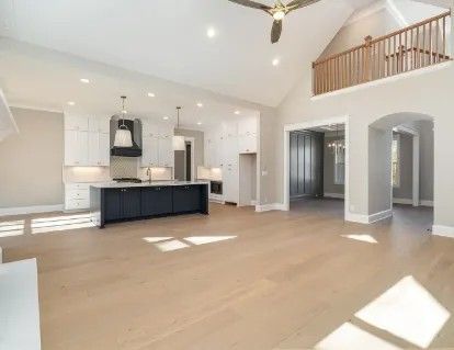 Open-concept living space with kitchen, dining area, and loft. Features hardwood floors, vaulted ceilings, and natural light.