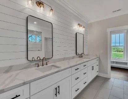 Bathroom with white cabinets, shiplap walls, two mirrors, and a window.