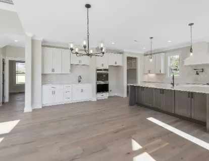 Modern kitchen with white cabinets, gray island, and hardwood floors.