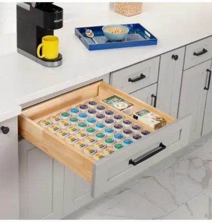 A drawer with coffee pods organized in a kitchen. A Keurig machine sits nearby.
