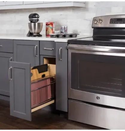 Gray kitchen cabinet with pull-out drawer, next to a stainless steel oven.