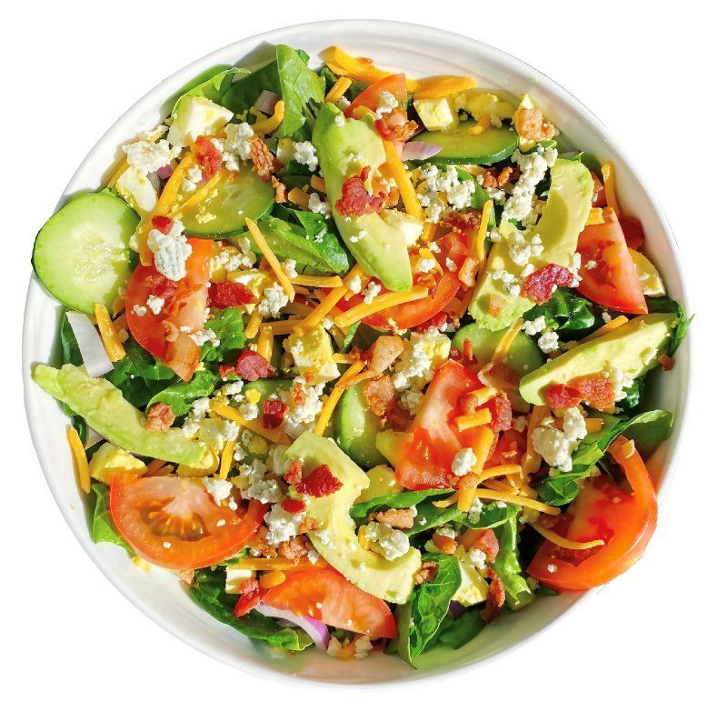 A salad with tomatoes , avocado , cheese and bacon in a white bowl