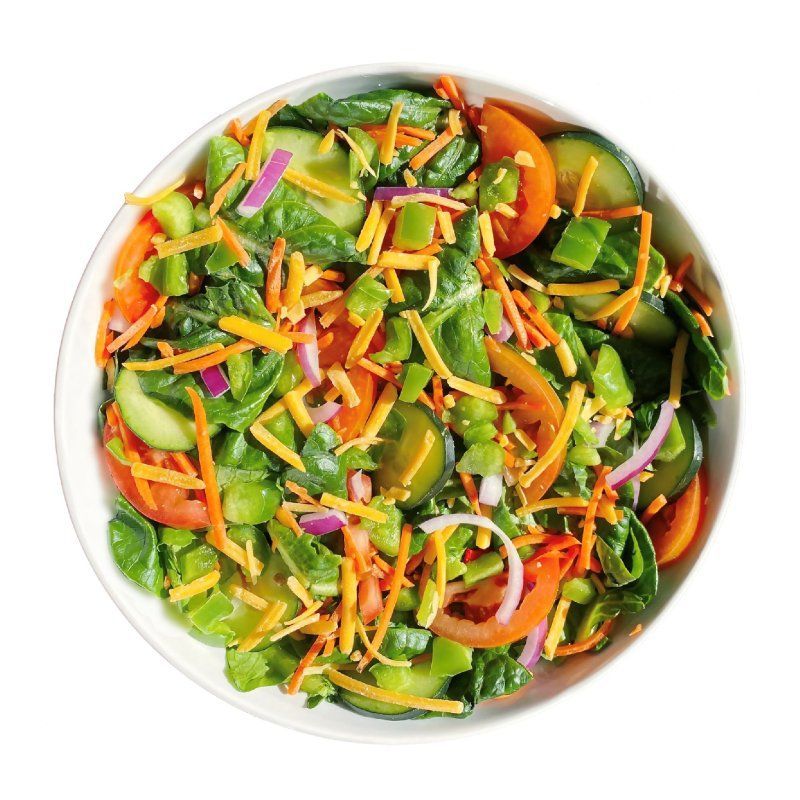 A salad with tomatoes , carrots , cucumbers , spinach and cheese in a white bowl.