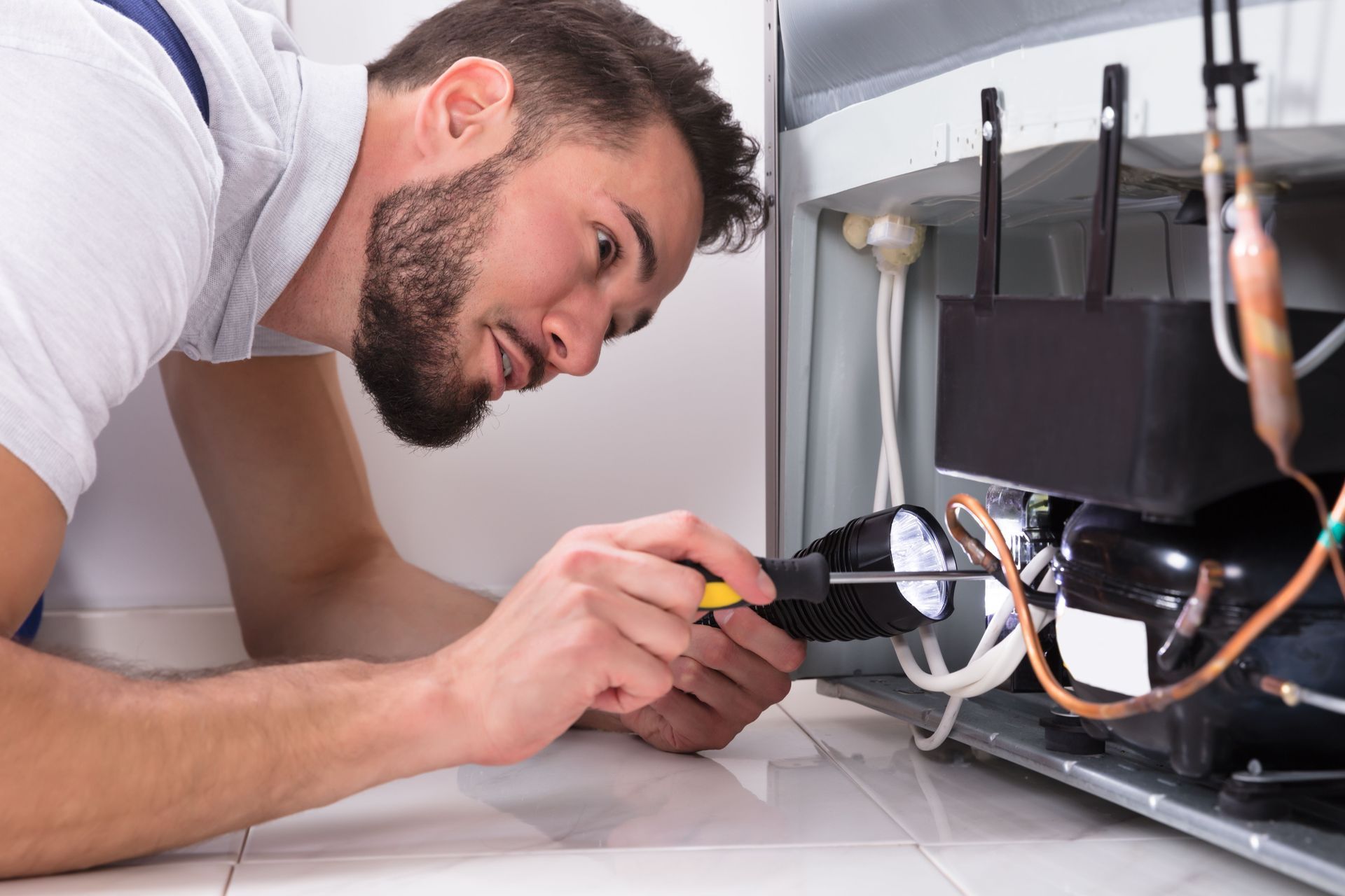 Technician inspecting wiring inside a wall-mounted TV with a screwdriver