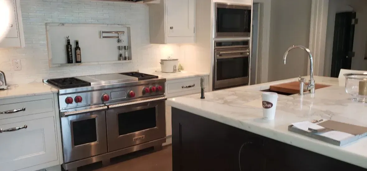 Modern kitchen with stainless steel stove, white cabinetry, and a dark island countertop